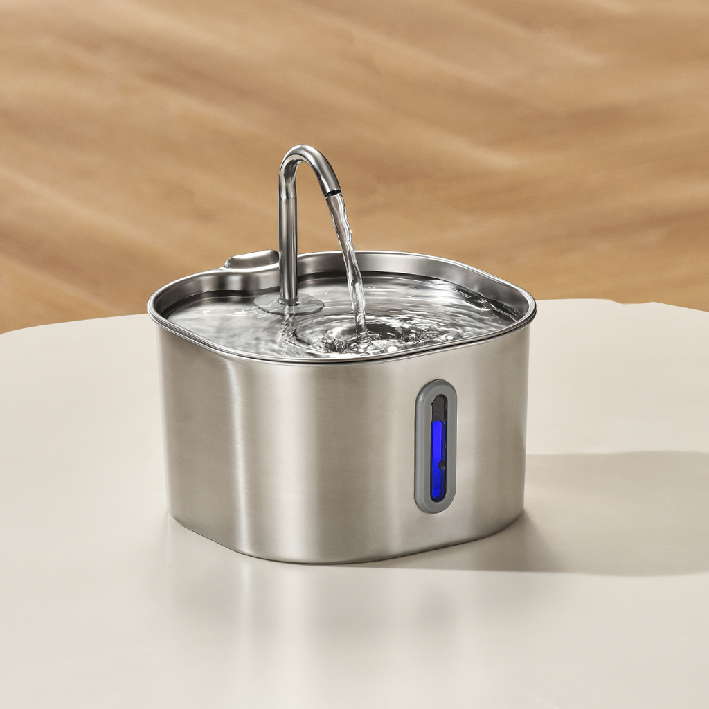 Stainless steel pet water fountain on a light surface with a wooden background